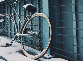 a-bike-covered-in-snow-parked-against-a-fence