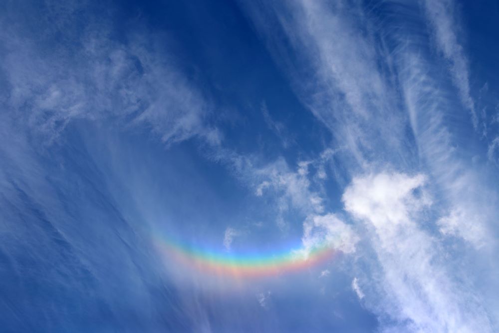 Upside down multi-coloured rainbow arc in blue sky