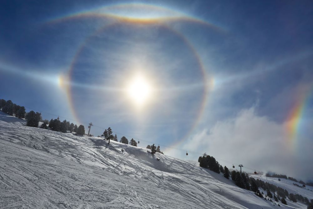 Halo of light surrounding the sun with a mountain in foreground