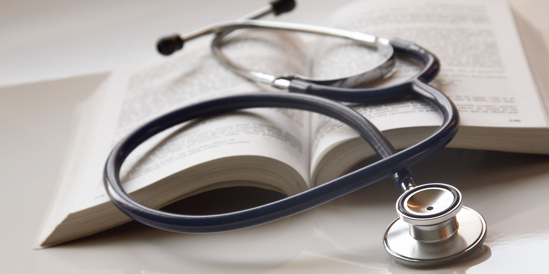 A stethoscope on top of an open book.