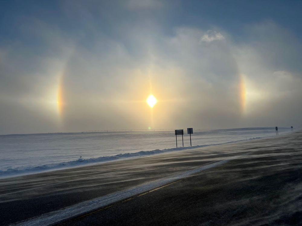 Bright spots appearing either side of the sun over a beach