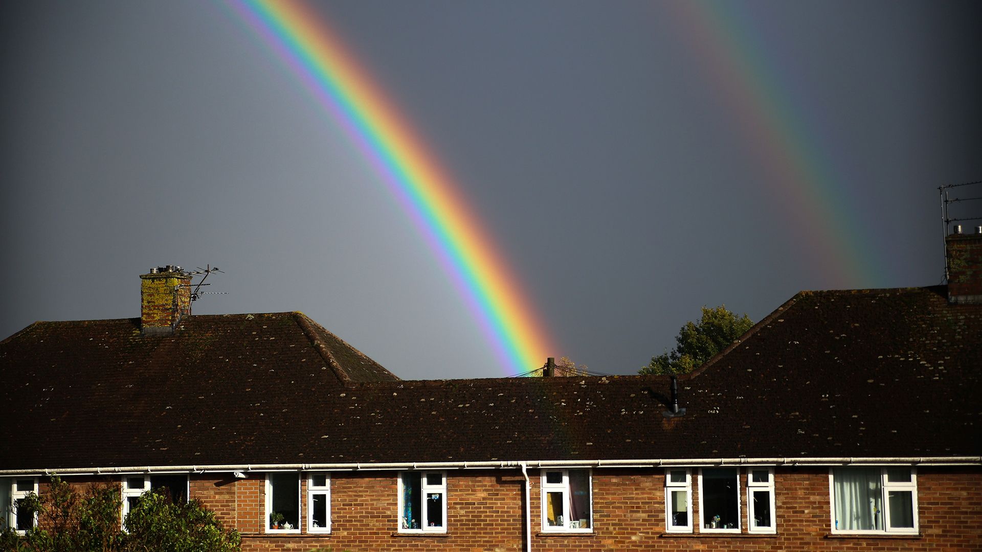 Double rainbow appearing over roofs of houses
