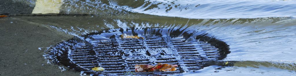 A flooded drain in a water-logged road.