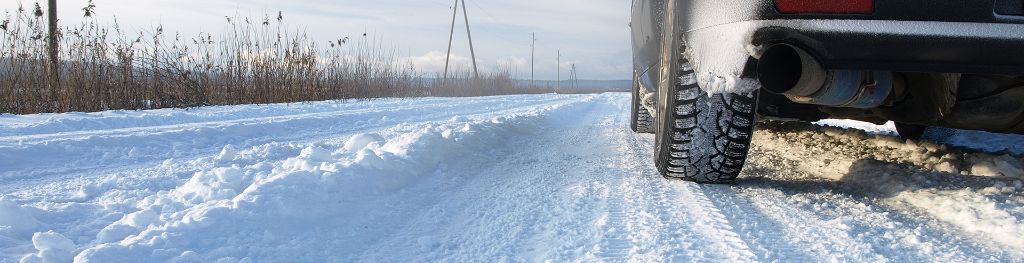 Close up of a the passenger back tyre of a car leaving tracks on a snowy road.