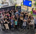 Participants of the NASA Space Apps challenge stood in a large group at the Met Office and waving for the camera.