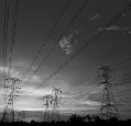Grey picture of power masts and cables before sky with a few clouds