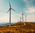 Wind turbines on hills before blue sky with some cloud cover
