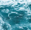 A blue-green ocean surface with waves and sea foam.