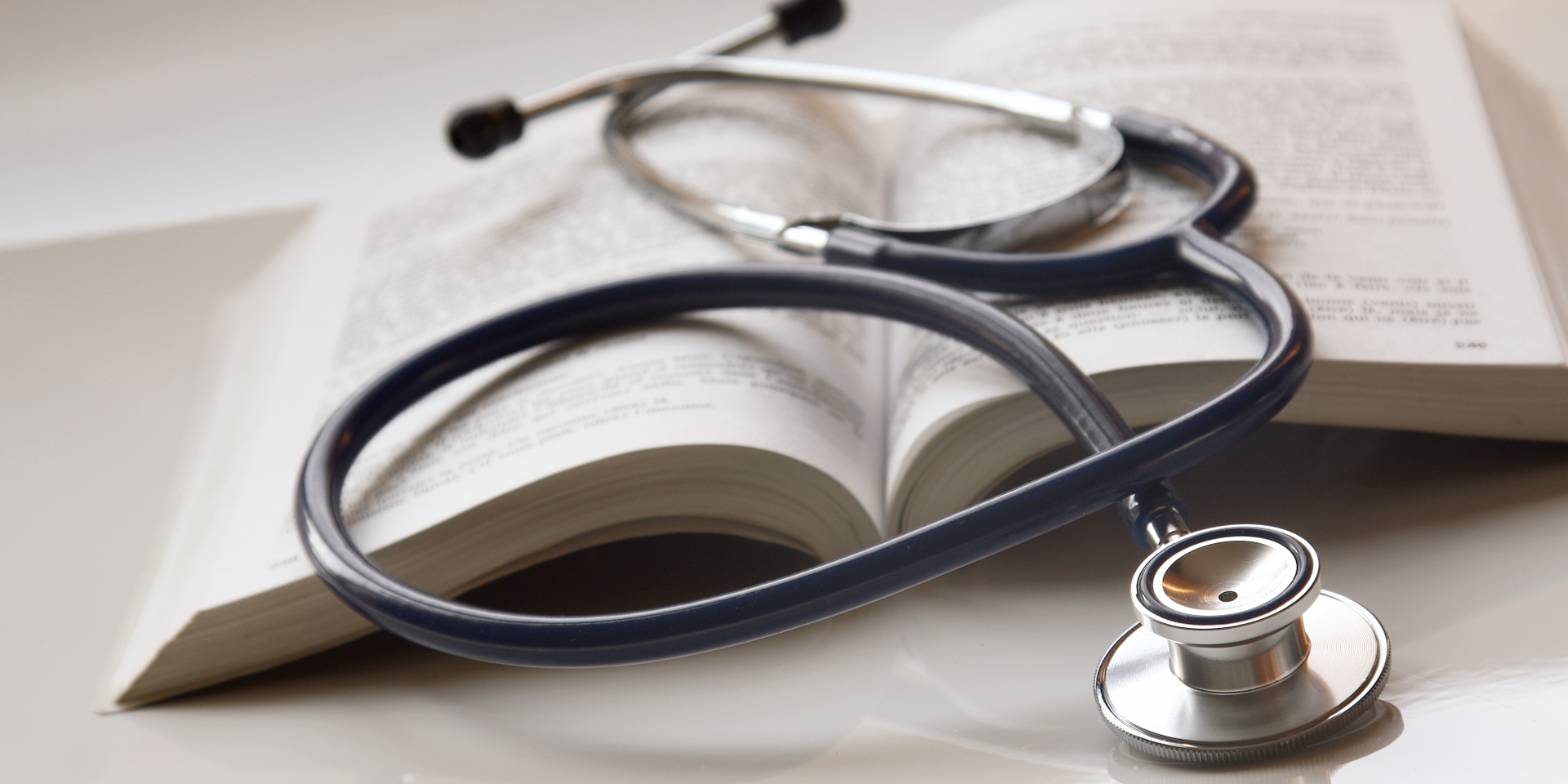A stethoscope on top of an open book.
