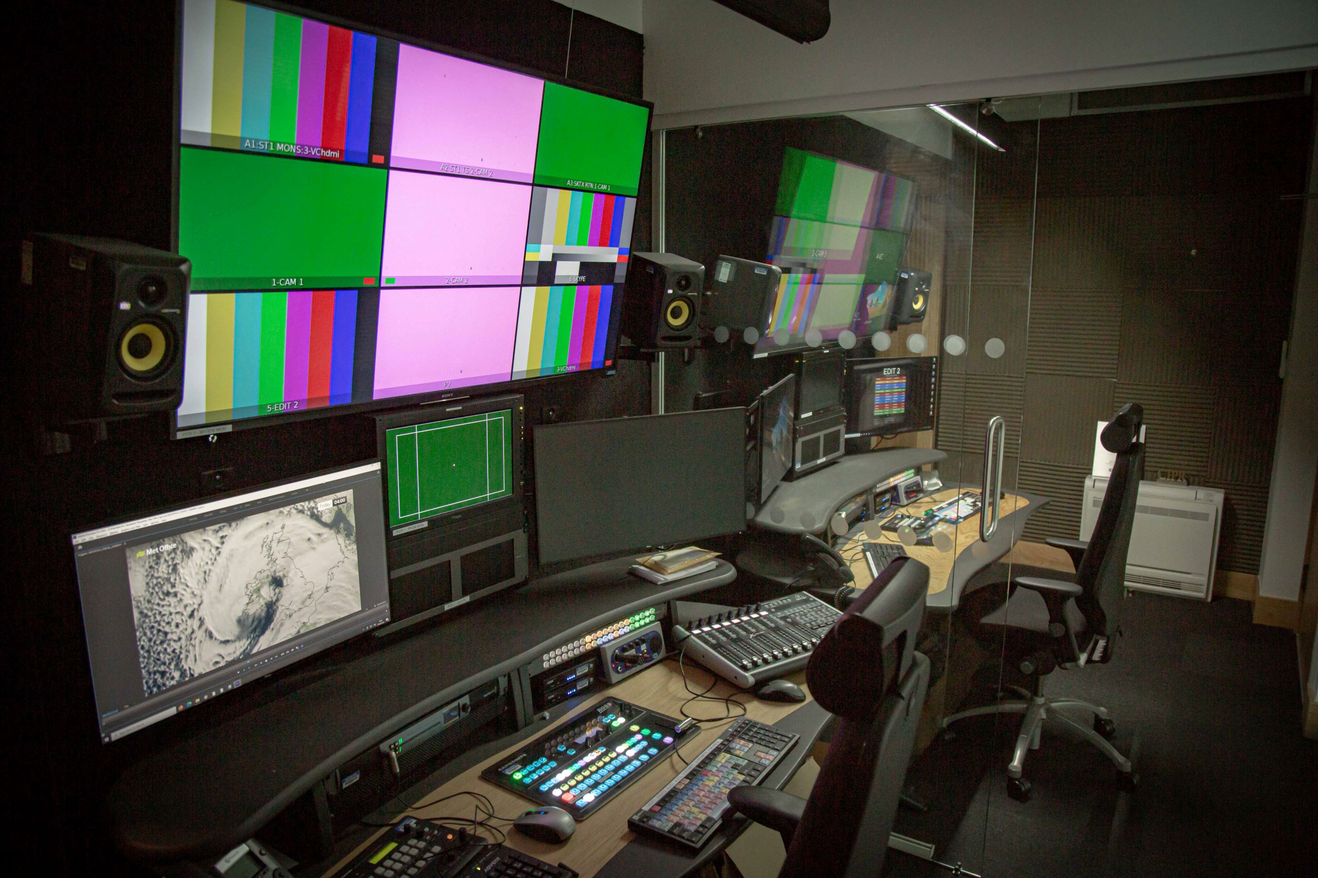 Behind the scenes in the Met Office studio, with multiple computer screens on the production desk