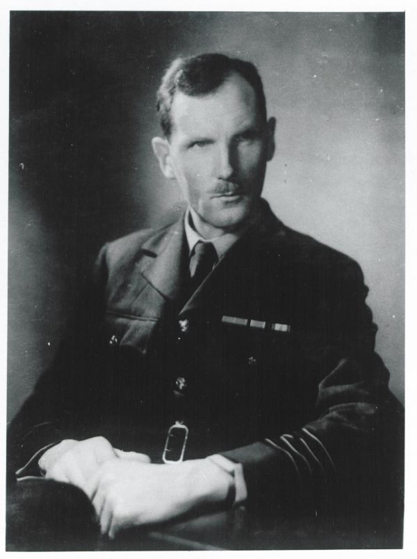 A black and white portrait photograph of Group Captain J. M. Stagg from the Met Office.