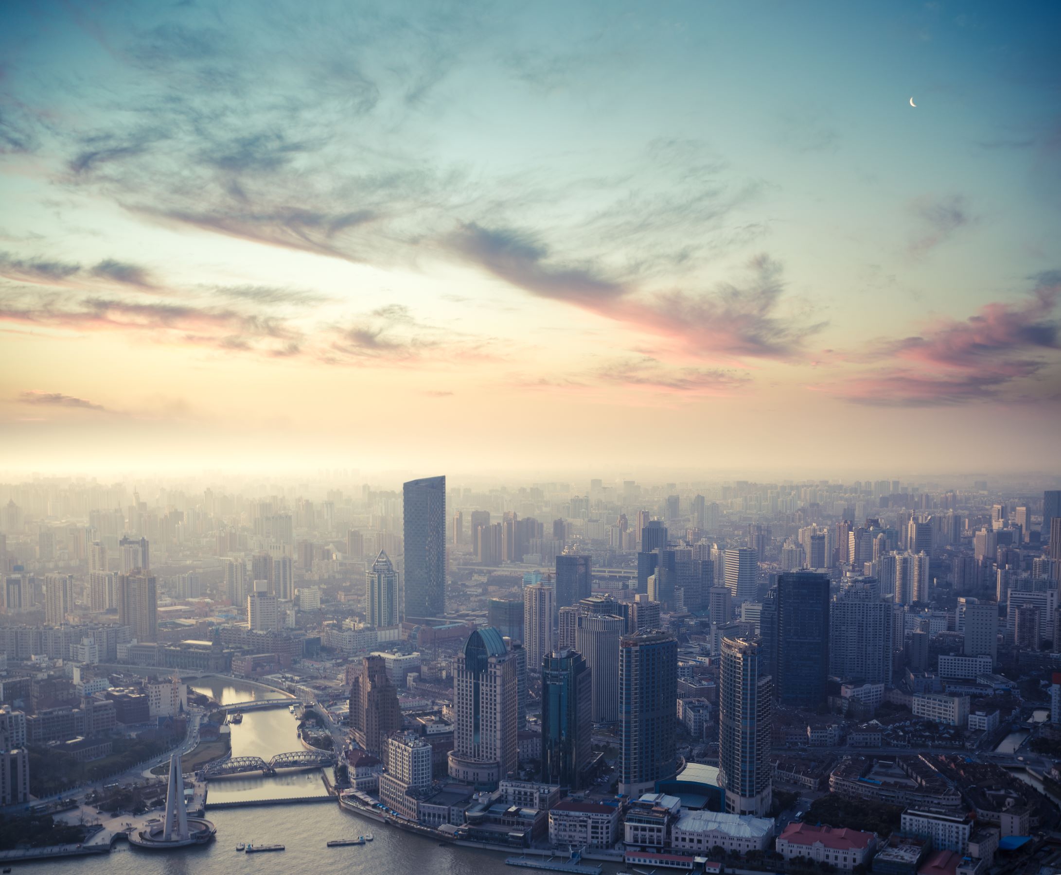 Decorative image showing a city skyline from the air with clouds in the sky