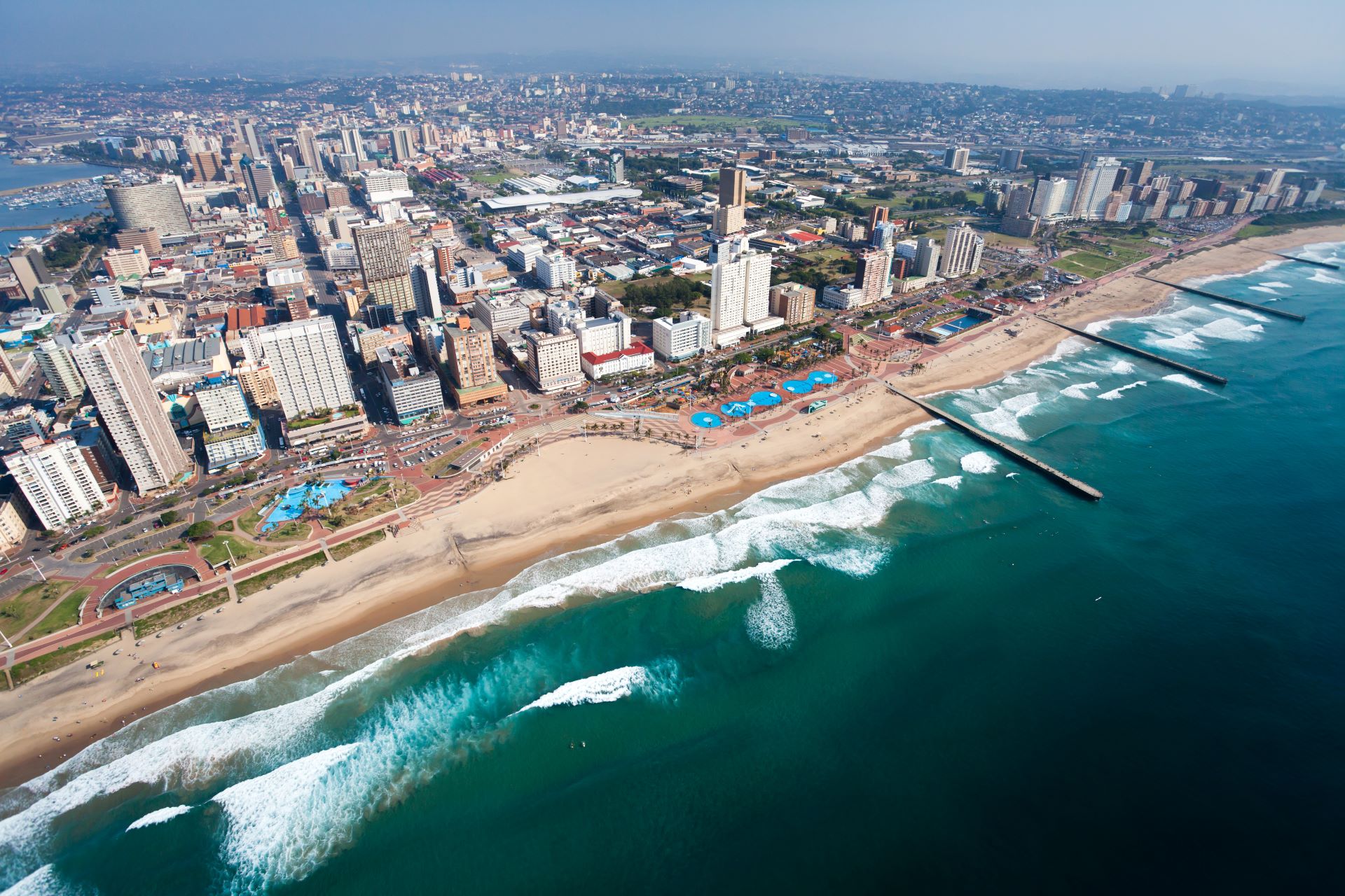 Decorative image showing an aerial view of the coastline in South Africa with beaches and city buildings
