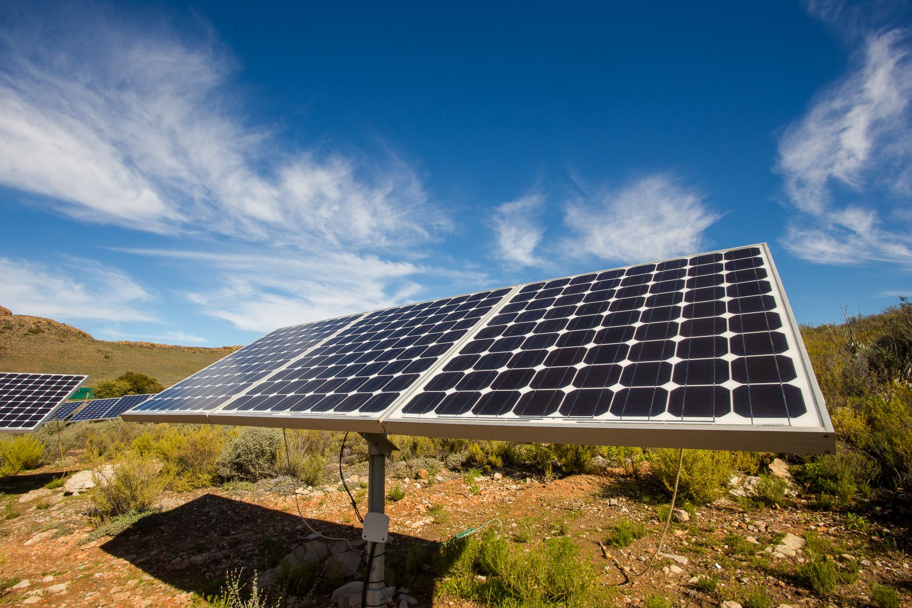 Decorative image showing a solar panel on grass with blue sky above