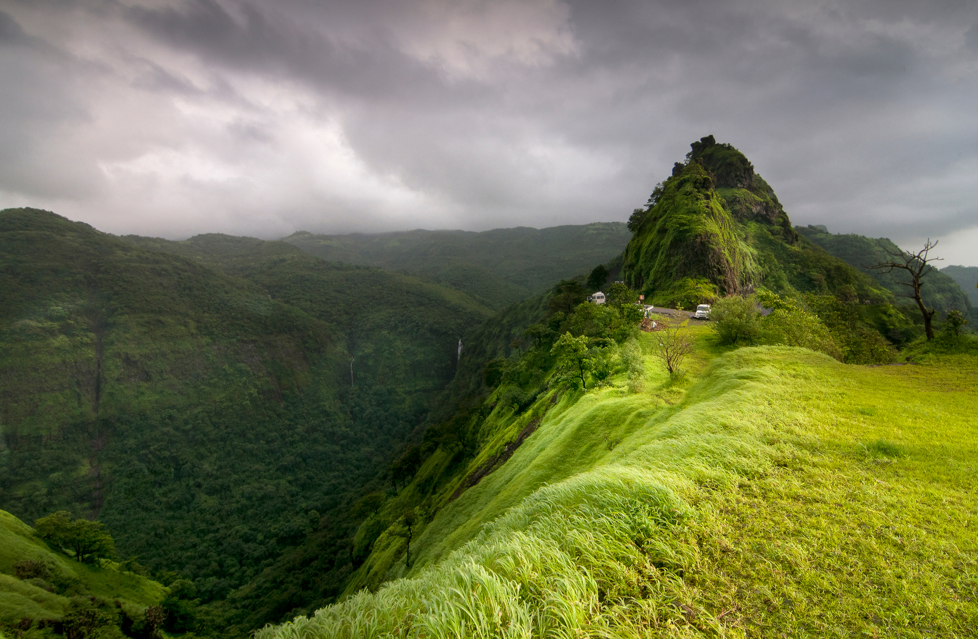 Photo of the Western Ghats showing mountains covered in green vegetation and trees and grey clouds in the sky