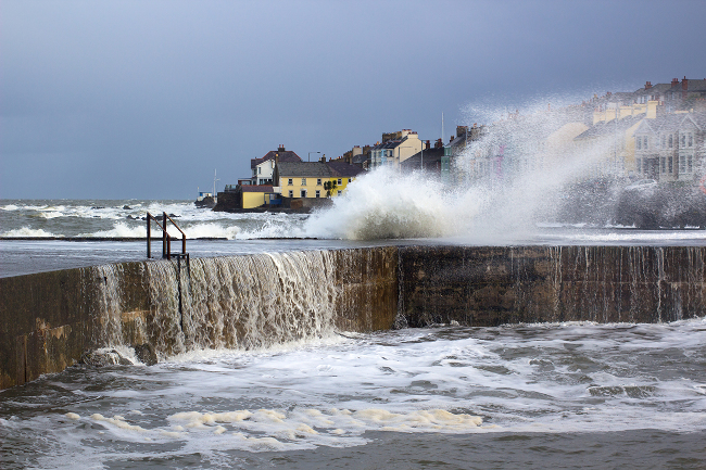 Stormy sea with waves crashing up against a sea wall.