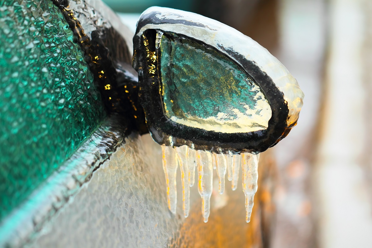 Car side mirror covered with ice and icicles