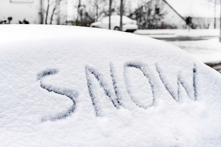 The word 'snow' written in the snow on a car